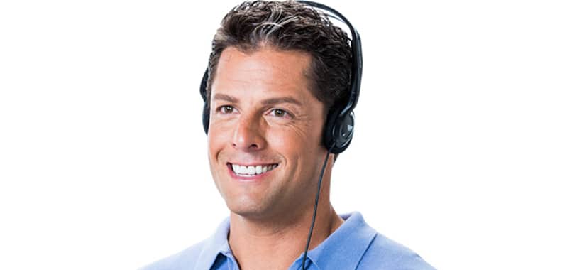 Hombre de mediana edad con cabello oscuro vistiendo una camisa de cuello azul sonriendo mientras usa audífonos sobre la cabeza